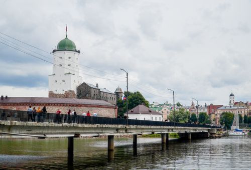 Free Vyborg Castle and pedestrian bridge over a calm river in Vyborg, Russia, on a cloudy day. Stock Photo