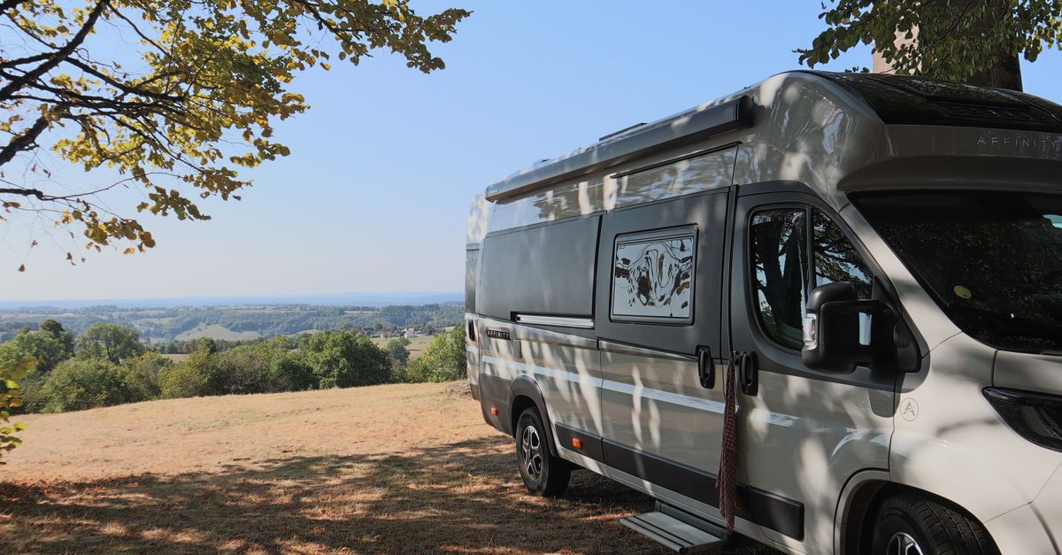 Camping-car garé sous un arbre face à la campagne française