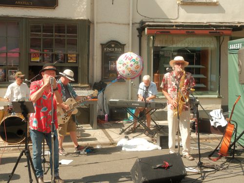 Free A lively street band performs with instruments and a celebratory balloon in an outdoor setting. Stock Photo