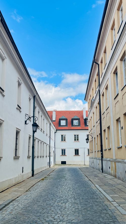 Free Serene cobblestone street flanked by historic European architecture under a clear blue sky. Stock Photo