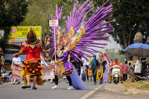 Free Colorful parade featuring participants in elaborate traditional costumes and large wings in a lively street setting. Stock Photo