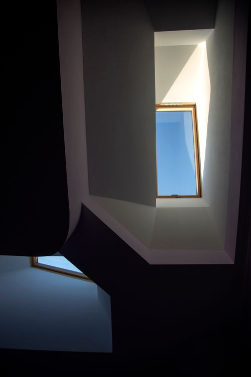Free A view of two modern skylights in a dark interior, framing a bright blue sky. Stock Photo