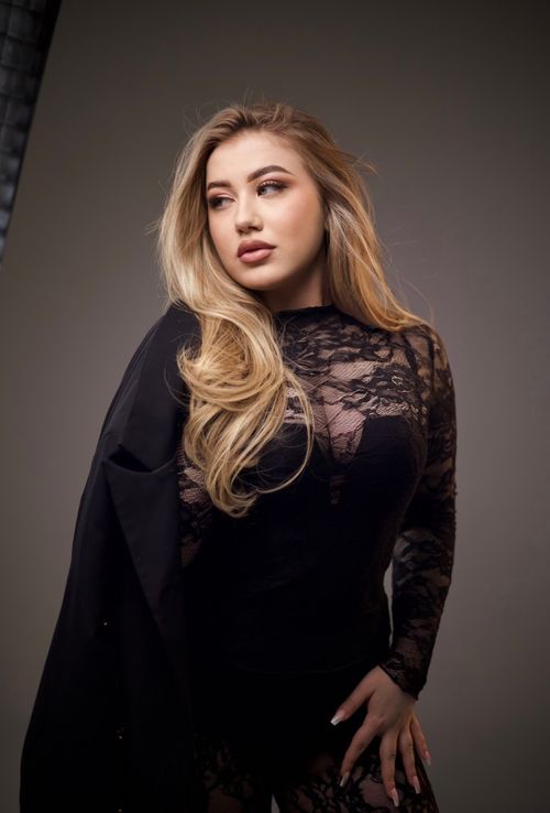 Free Chic portrait of a blonde woman in a black lace dress, exuding elegance. Stock Photo