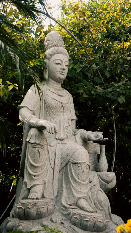 Free A serene stone Buddha statue surrounded by lush greenery in Ho Chi Minh City, Vietnam. Stock Photo