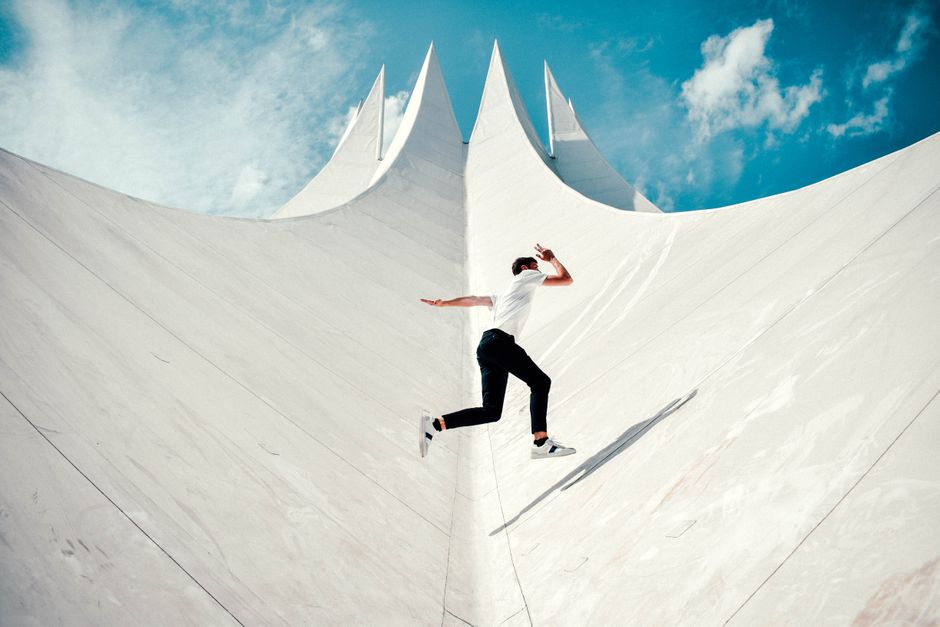 A person jumps energetically against a striking modern architectural backdrop. A person jumps energetically against a striking modern architectural backdrop.