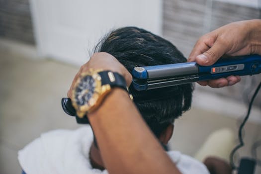 Close-up of a hairdresser styling a client's hair using a straightener in a barbershop.