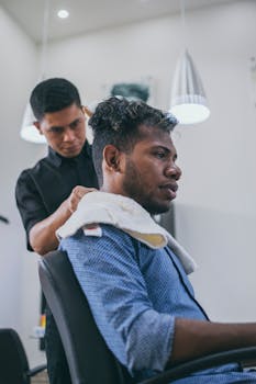 Man getting a haircut in a modern barbershop, captured in natural light.