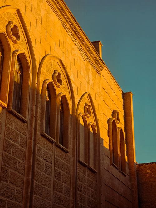 Free Beautiful historic facade with arched windows bathed in golden sunset light. Stock Photo