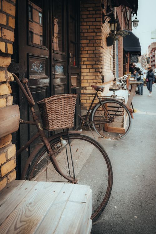 Free Two vintage bicycles with wicker baskets outside a rustic brick building on a city street. Stock Photo