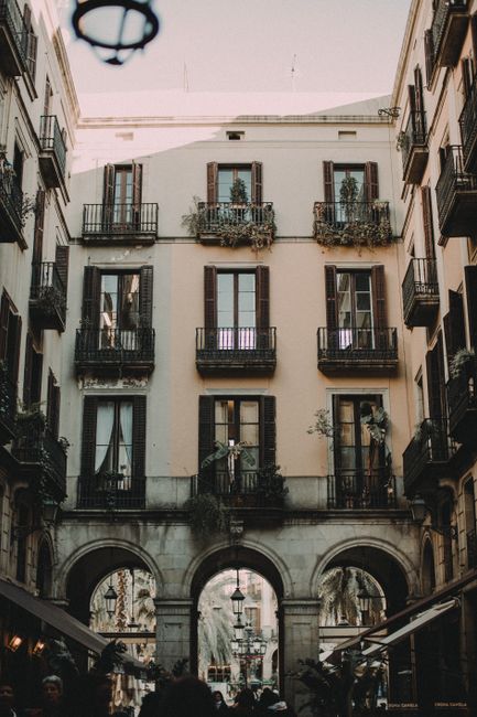 A vintage architectural scene featuring ornate balconies and arches on a building in Barcelona, Spain.