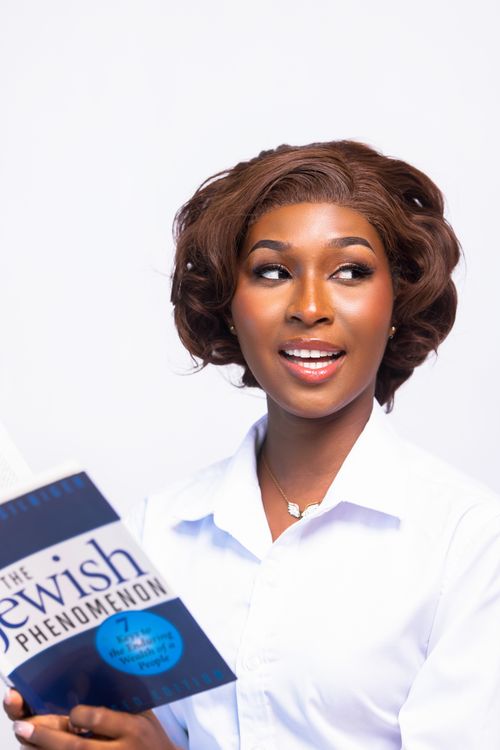 Free Smiling woman in white shirt holding a book titled 'The Jewish Phenomenon'. Stock Photo
