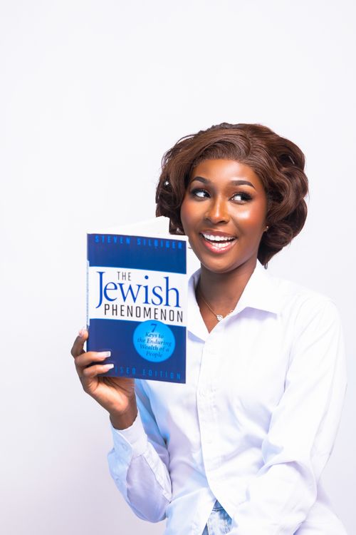 Free Person joyfully holds 'The Jewish Phenomenon' book, showcasing knowledge enthusiasm. Stock Photo