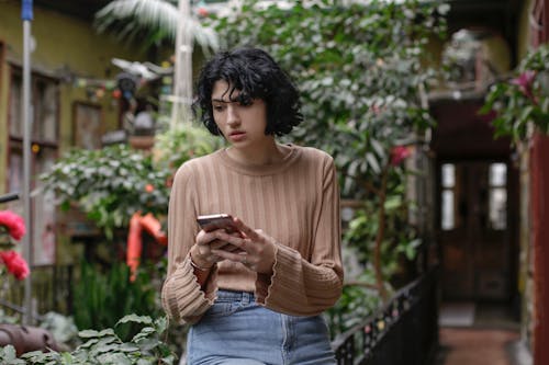 Woman in Brown Sweater Holding Smartphone