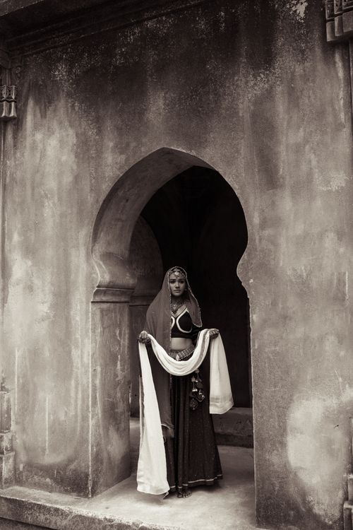 Free A woman in traditional Indian clothing stands gracefully in an archway, exuding cultural elegance. Stock Photo