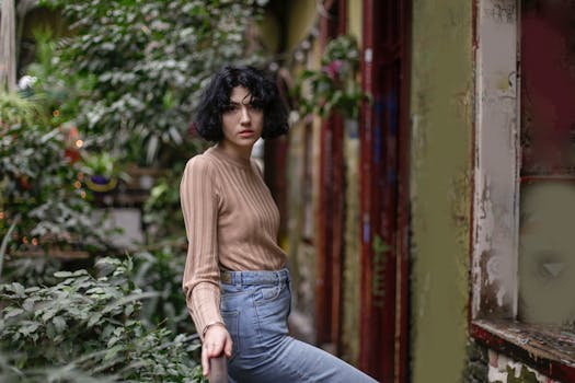 Fashionable woman with short hair posing confidently in a lush outdoor setting.