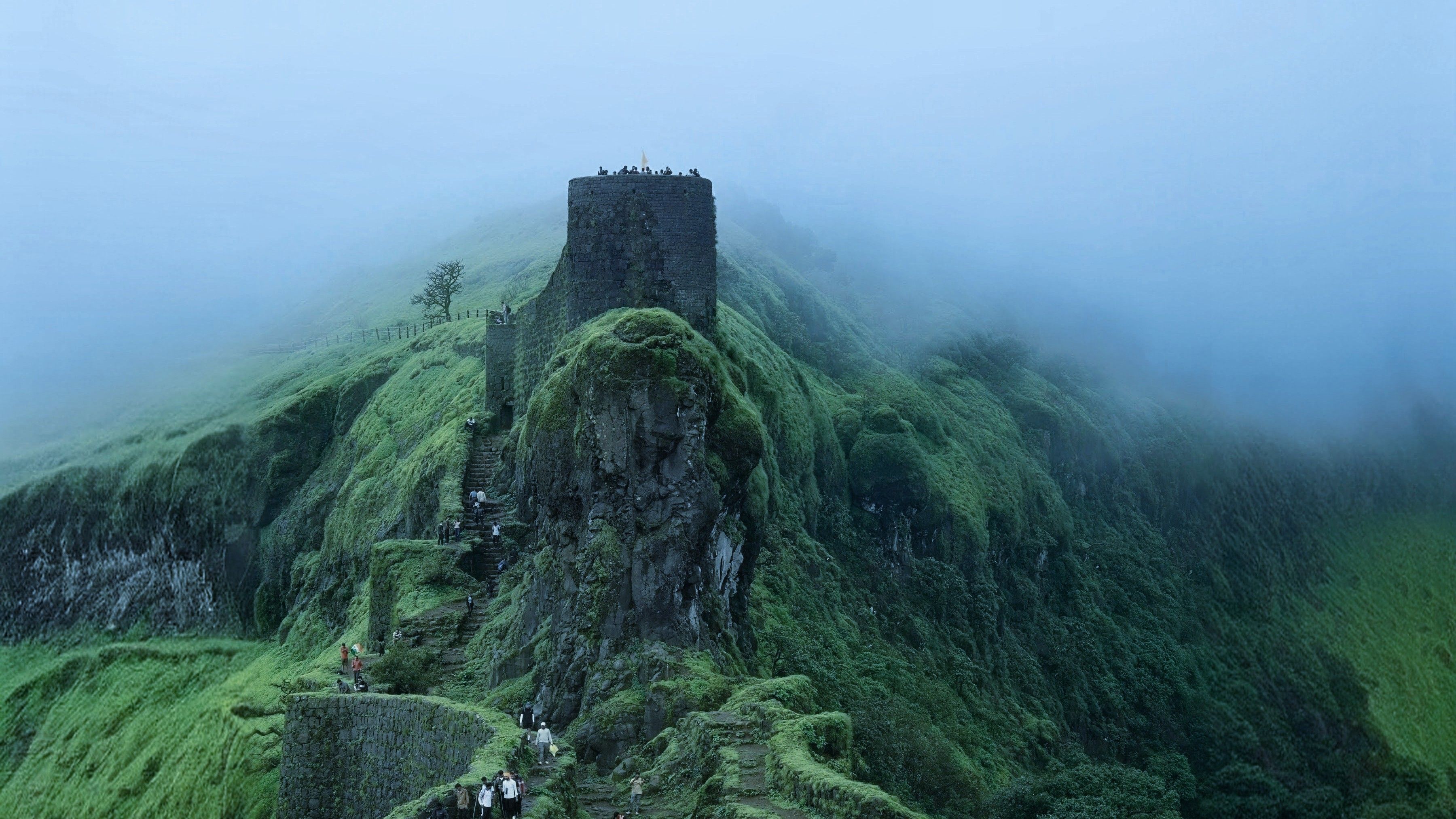 Waterfall in full flow through misty green hills in the Western Ghats