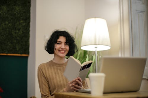 Free Woman in Brown Long Sleeve Shirt Holding a Book Stock Photo