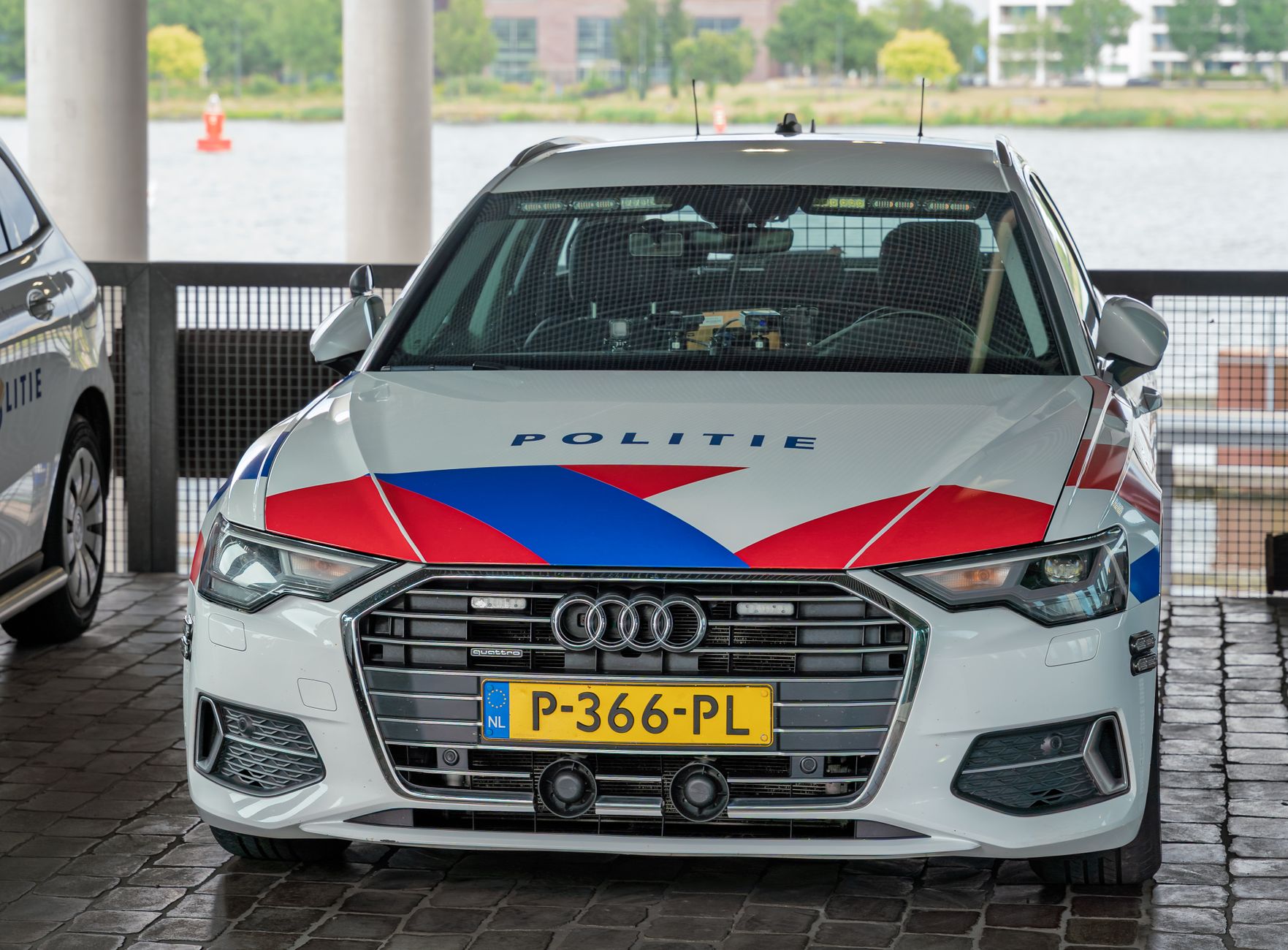 Een Nederlandse politieauto met 'Politie'-markering, geparkeerd in een stedelijke omgeving, toont zijn kenmerkende rood-wit-blauwe kleuren.
