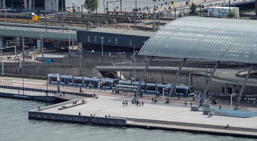 Free Aerial view of a bustling urban transit hub with trains and trams operating on a cloudy day. Stock Photo