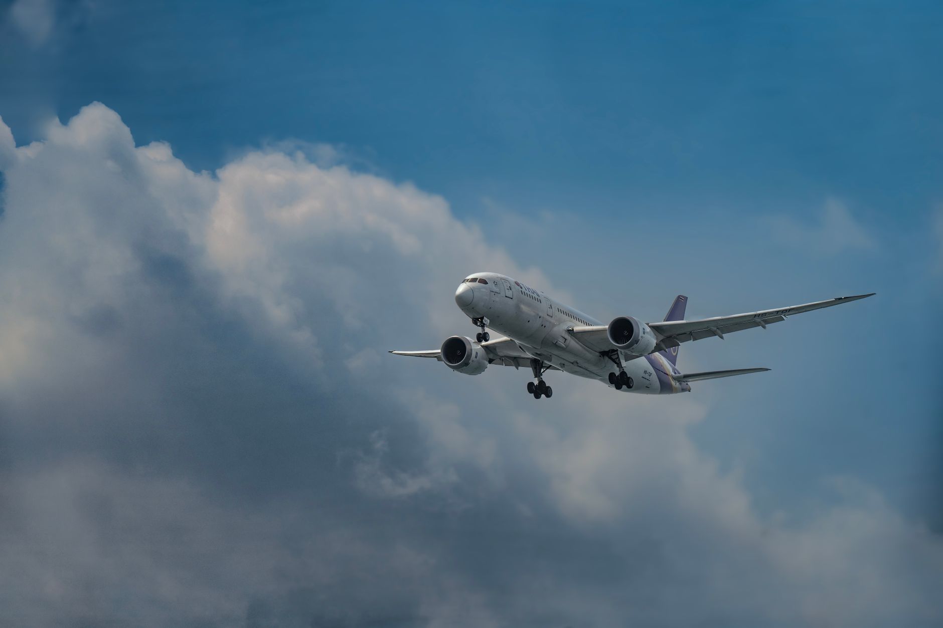 A commercial airplane soaring through a cloudy sky during daytime.