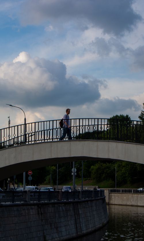 Free A person walks on a bridge in Москва, with dramatic clouds and soft light enhancing the scene. Stock Photo