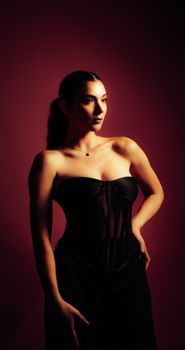 Stunning portrait of a woman in a black dress against a dark background, exuding elegance.