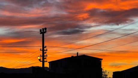 Sunset over rooftops and power lines, photo by Adem Albayrak on Pexels