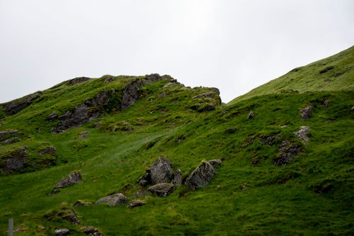 Free Scenic view of grassy hills with rocky outcrops under a cloudy sky. Stock Photo