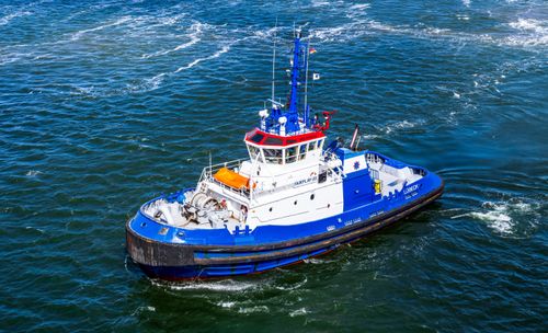 Free A vibrant blue and white tugboat sails through the waters near Rostock, Germany. Stock Photo