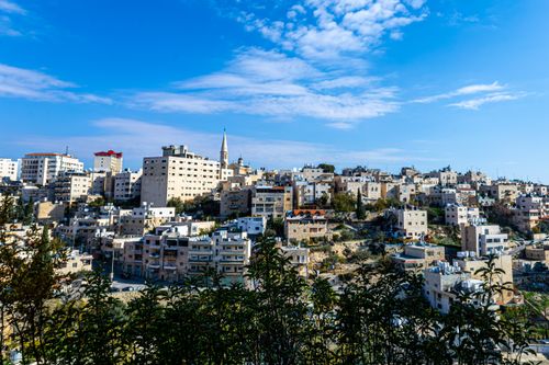 Free Explore the cityscape of Bethlehem with its distinctive architecture under a bright blue sky, showcasing traditional Middle Eastern urban life. Stock Photo