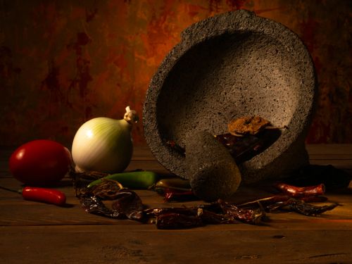 Free A selection of Mexican cuisine ingredients including chili peppers, onion, and a molcajete on a rustic table. Stock Photo