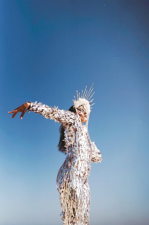 Free Person in artistic costume posing with outstretched arm against clear blue sky. Stock Photo