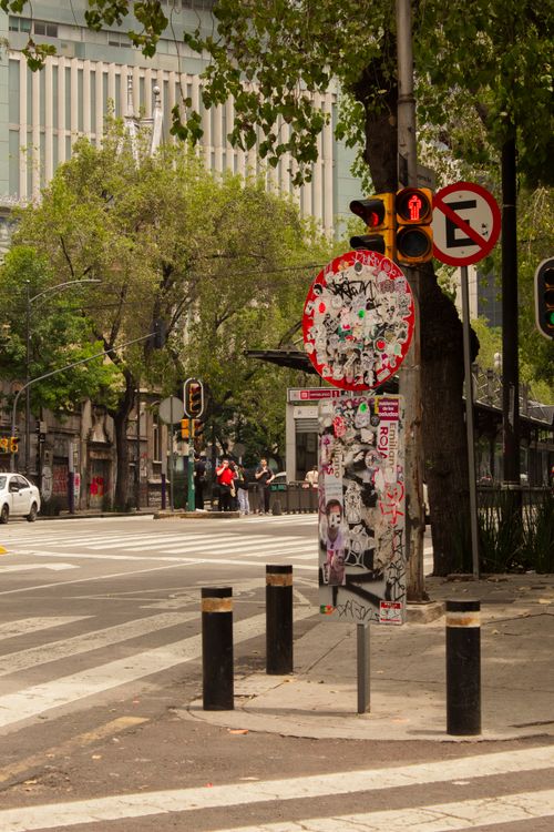 Free Urban street corner in Mexico City with sticker-covered sign and traffic light. Stock Photo
