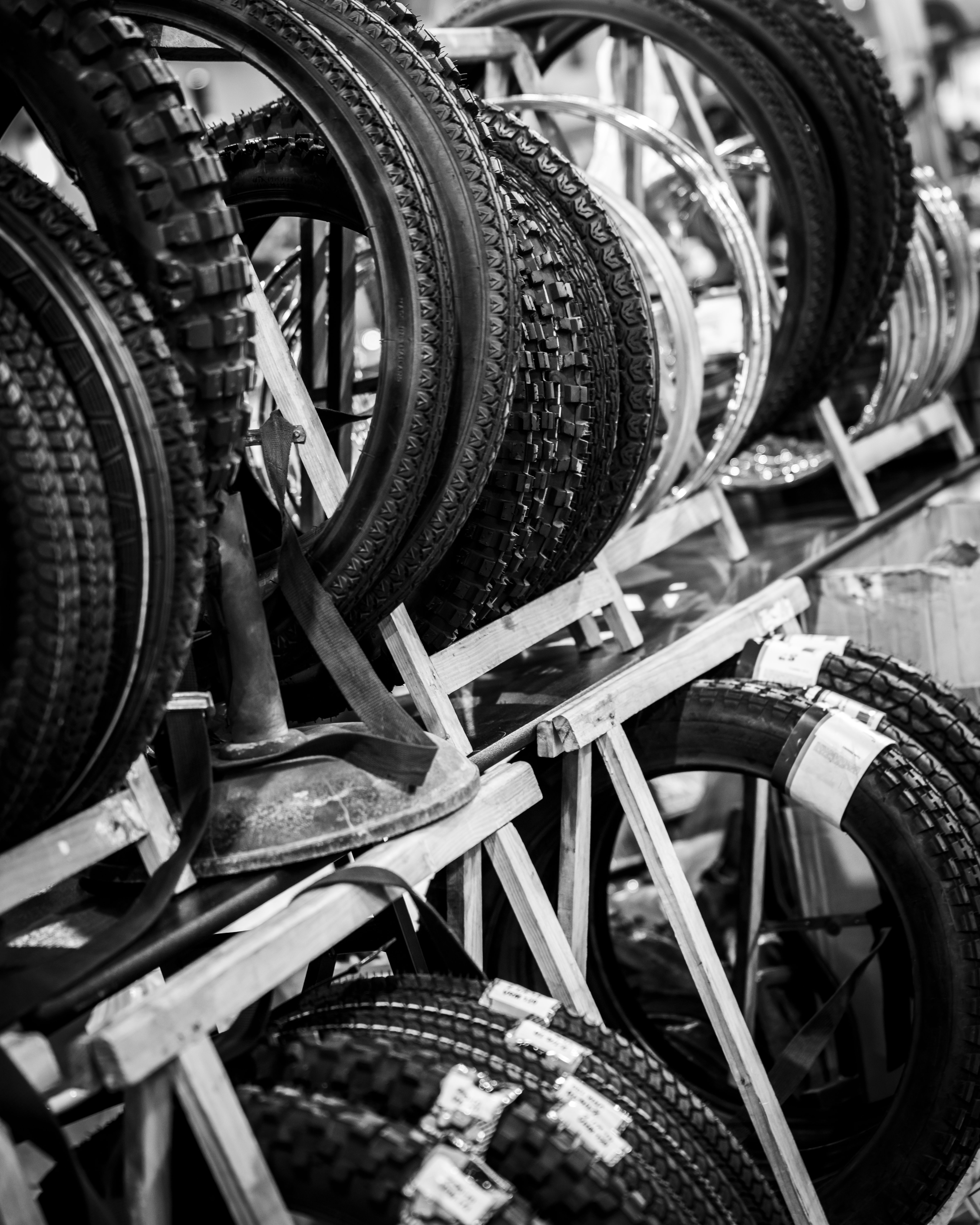 Rows of motorcycle tires on wooden racks in a shop, black and white.