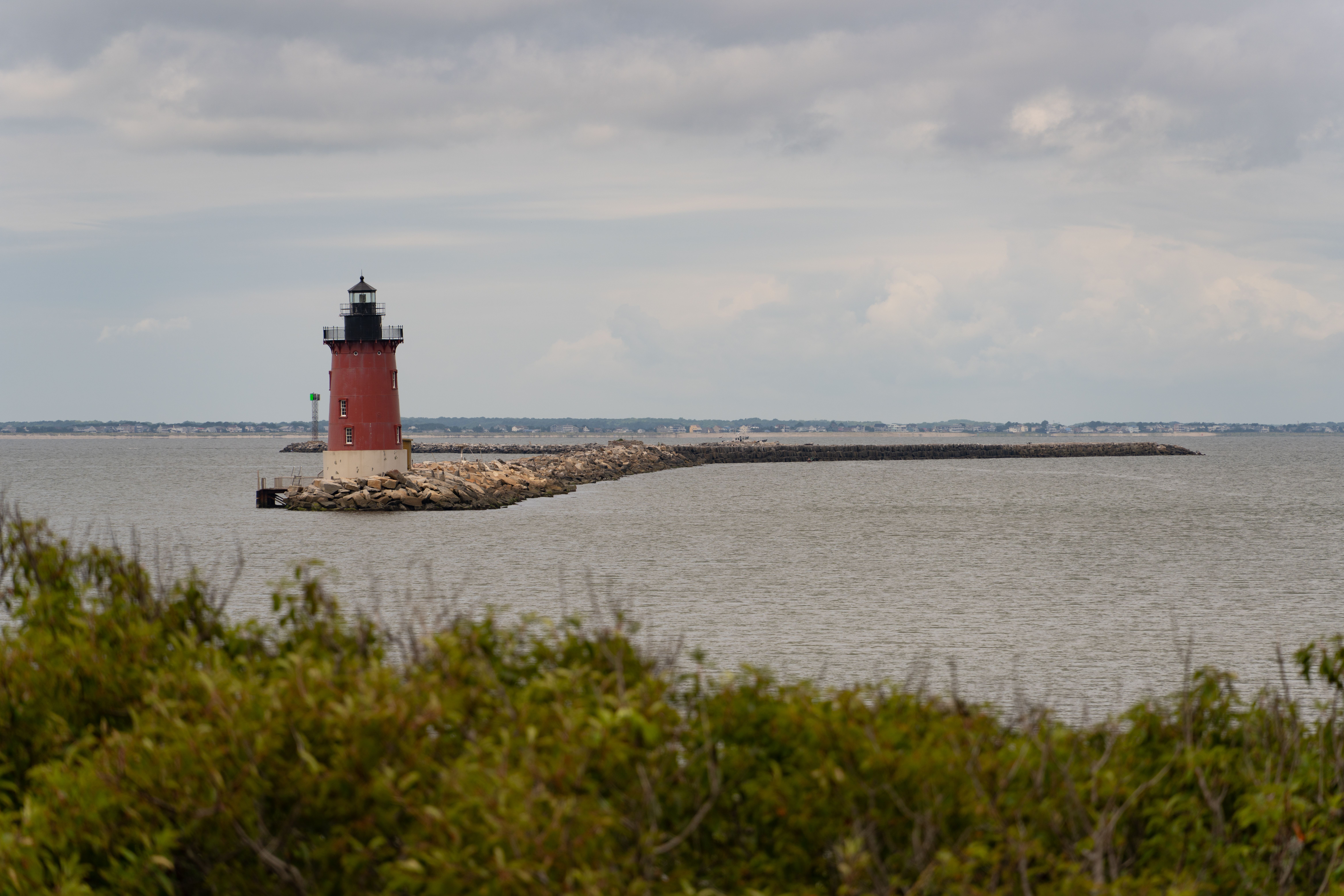 Scenic view of Breakwater Lighthouse in Lewes, Delaware, with dramatic cloudy sky over the sea.