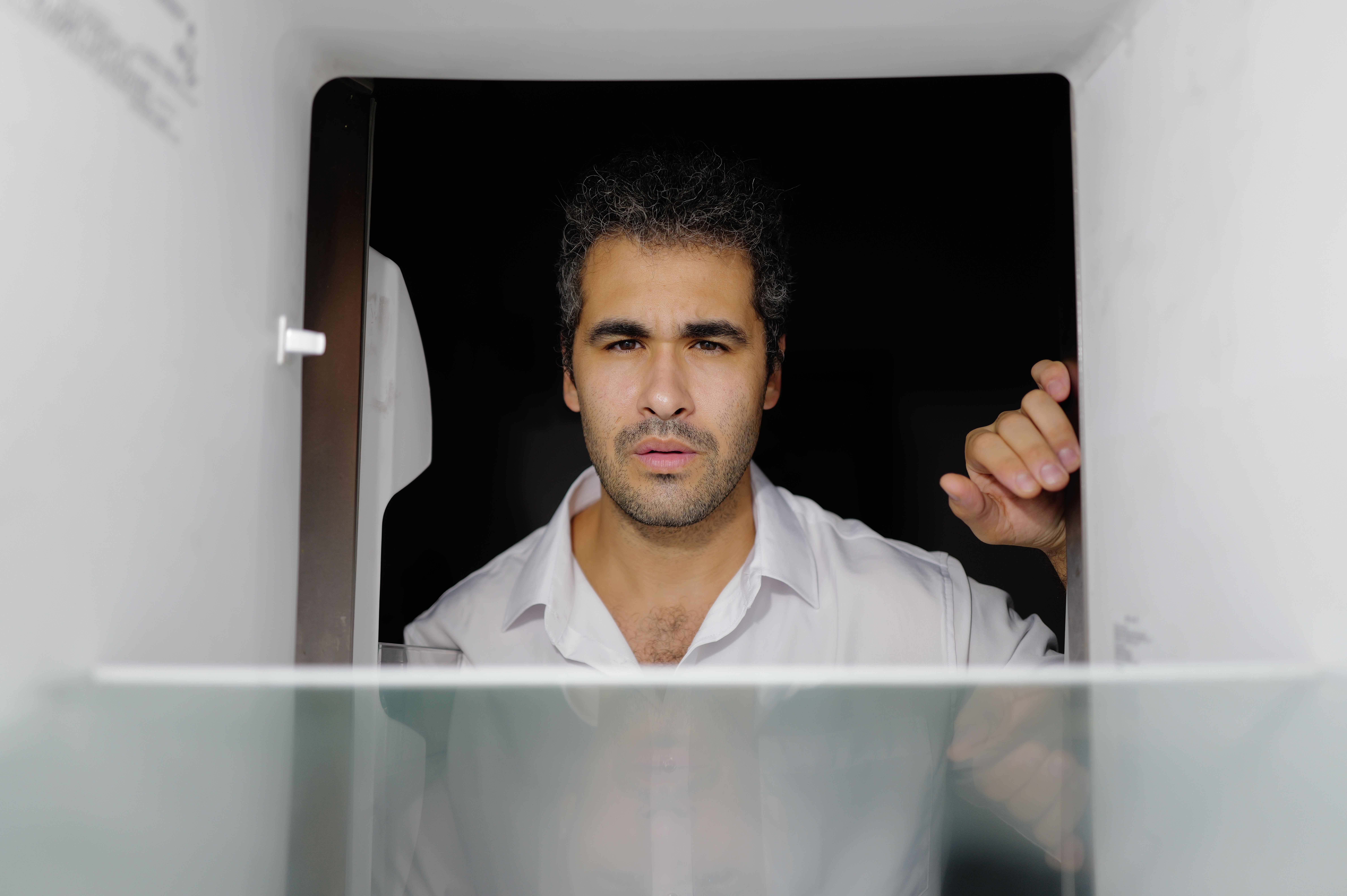 Concerned man looking into an empty fridge, symbolizing financial stress and rising food costs.