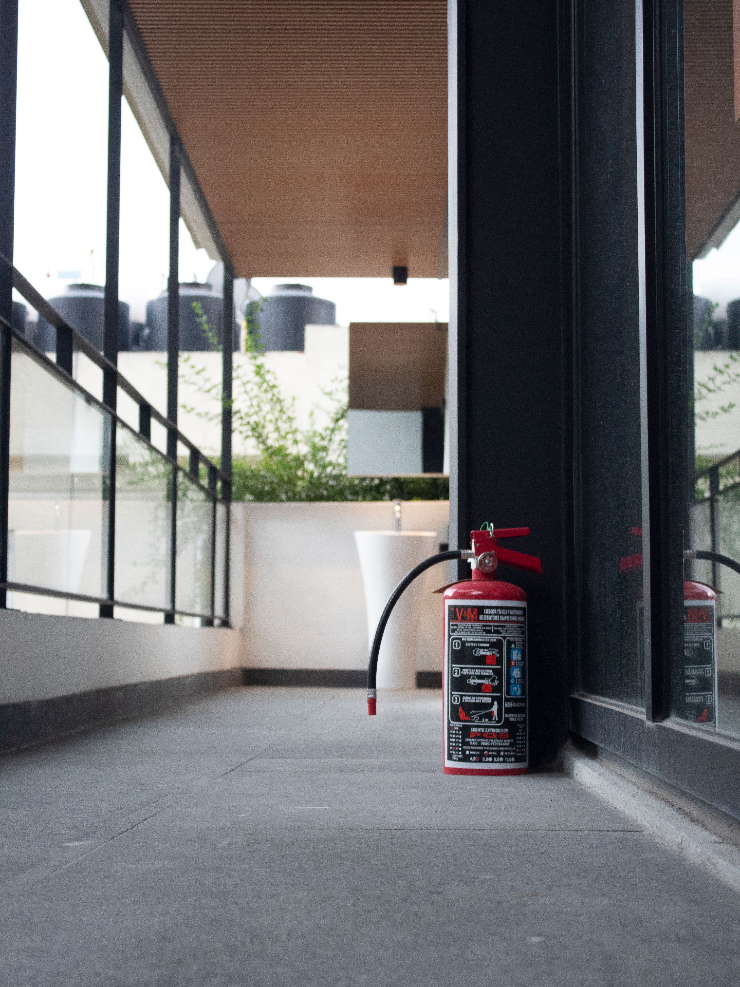 Red fire extinguisher in an outdoor corridor of a modern building in Ciudad de México.