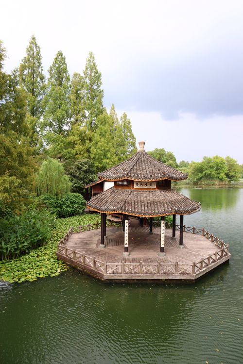 Free Beautiful octagonal pavilion by a lake surrounded by lush greenery in a tranquil setting. Stock Photo