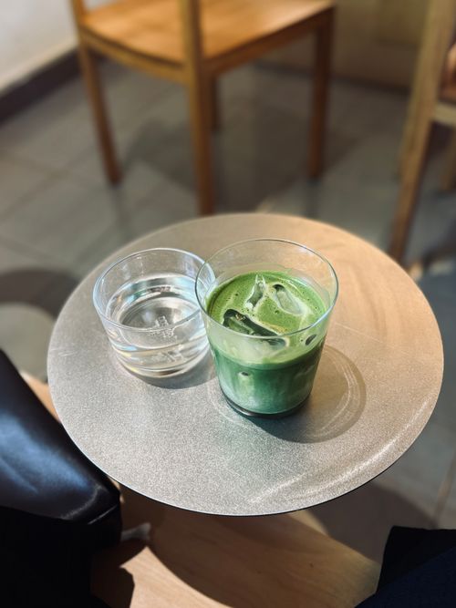 Free A refreshing iced matcha latte alongside a glass of water on a metallic cafe table. Stock Photo