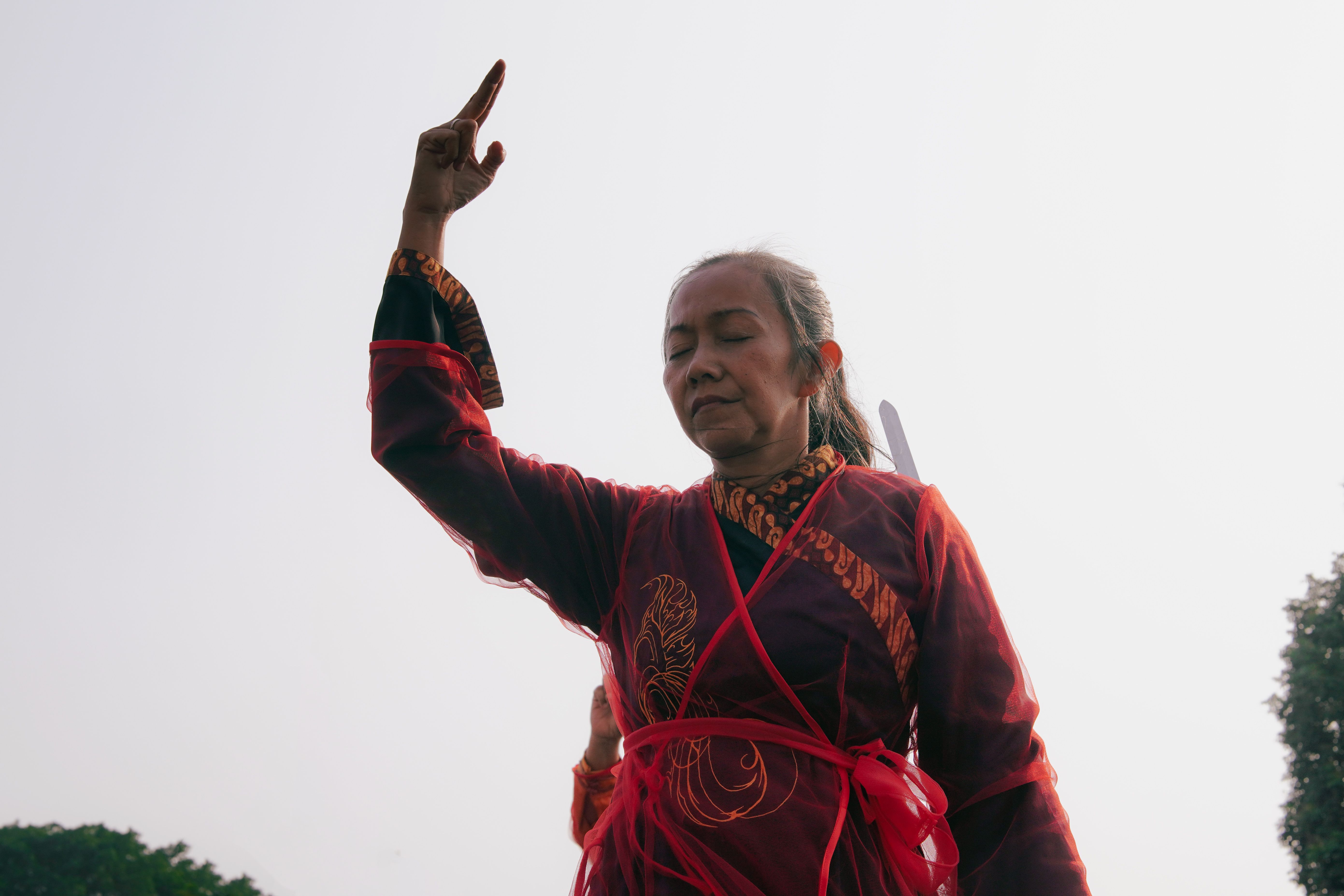 Woman performing Tai Chi in traditional attire in Yogyakarta, Indonesia, showcasing balance and concentration.