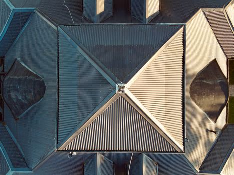 A geometric aerial view of a building's unique architectural roof design with shadows.