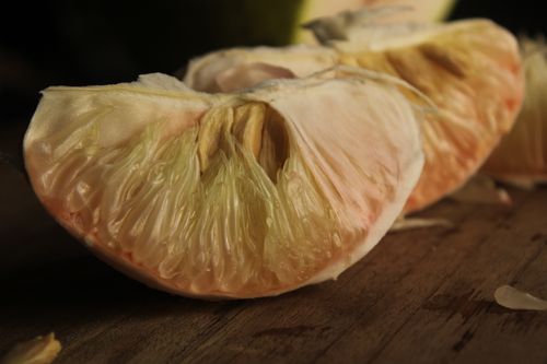 Free Detailed close-up of a juicy pomelo segment on a rustic wooden background. Stock Photo