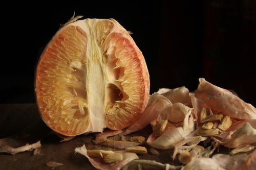 Free Freshly sliced pomelo with scattered peel in a warm, rustic setting. Perfect for food photography. Stock Photo