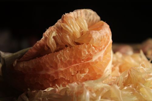 Free Detailed view of a peeled pomelo fruit showcasing its juicy segments in warm lighting. Stock Photo
