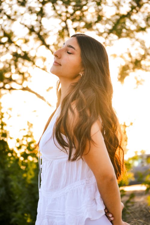 Free A young woman basks in warm sunlight, experiencing peaceful bliss outdoors. Stock Photo