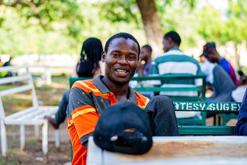 Free A cheerful man enjoying a sunny day in the park with friends in the background. Stock Photo