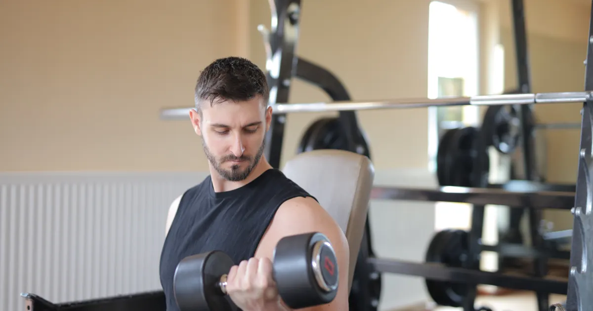 Man doing a dumbbell curl in a gym