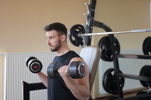 Man Holding Black and Red Dumbbells