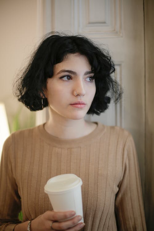 Woman in Brown Crew Neck Shirt Holding Disposable Cup