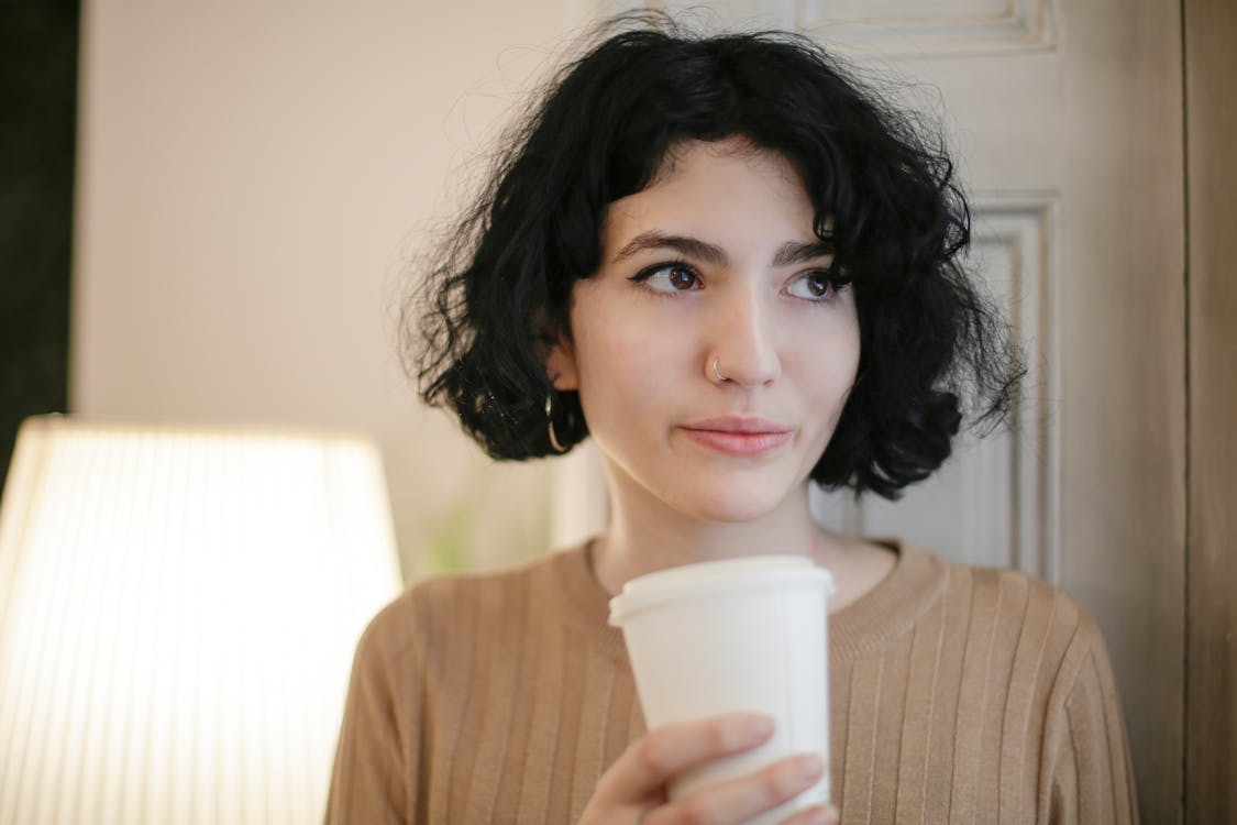 Free Woman in Brown Sweater Holding White Disposable Cup Stock Photo